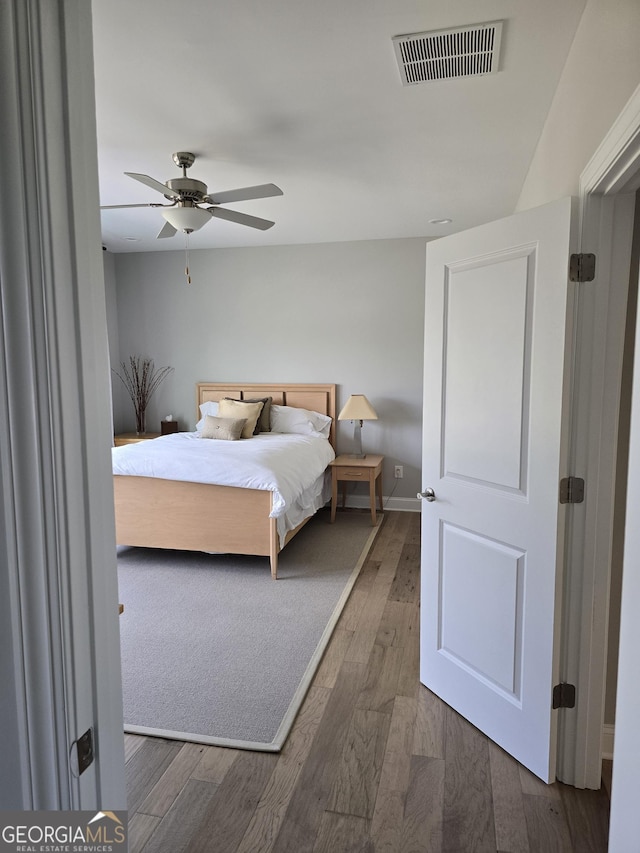 bedroom with a ceiling fan, baseboards, visible vents, and wood finished floors