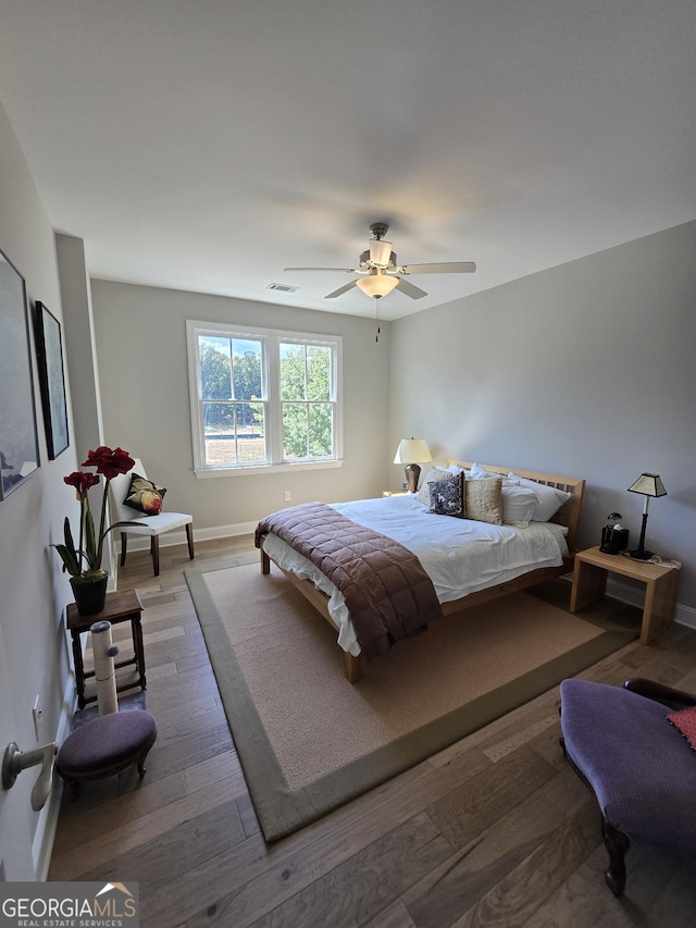 bedroom featuring baseboards, visible vents, ceiling fan, and wood finished floors