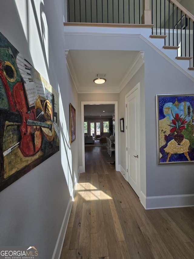 corridor with ornamental molding, baseboards, stairway, and hardwood / wood-style floors