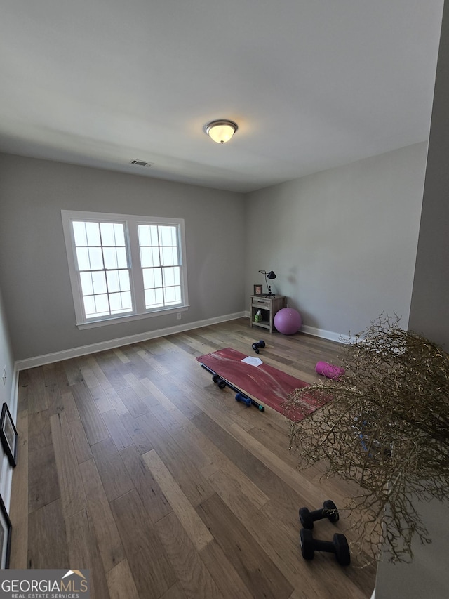 workout room featuring wood finished floors, visible vents, and baseboards