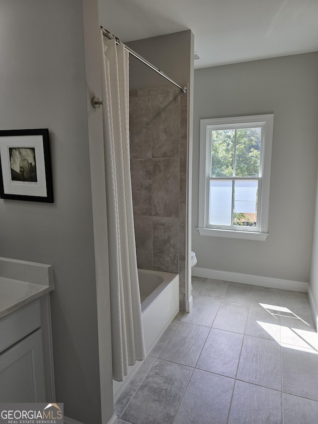 bathroom featuring toilet, shower / bath combo with shower curtain, vanity, baseboards, and tile patterned floors