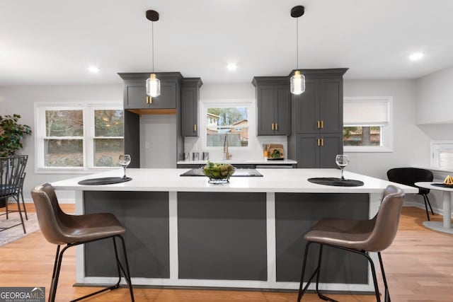 kitchen featuring a breakfast bar area, gray cabinets, and pendant lighting