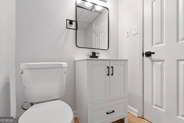 bathroom with hardwood / wood-style floors, vanity, and toilet