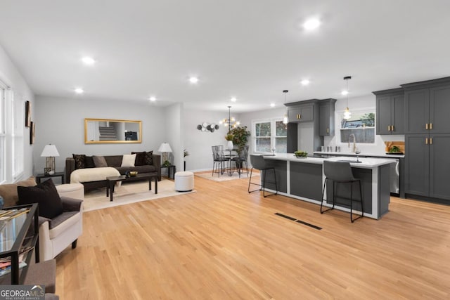 living room with a chandelier, sink, and light hardwood / wood-style floors