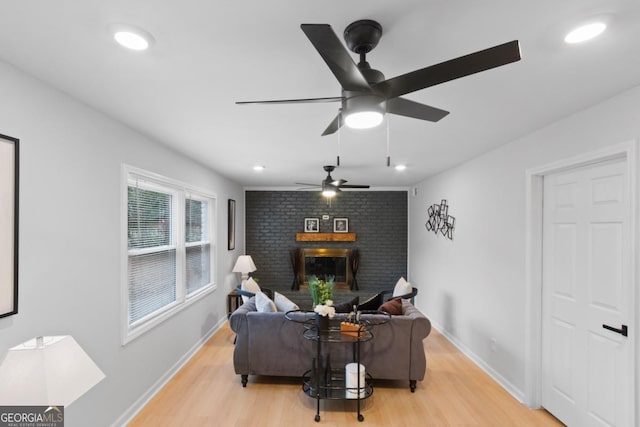 living room with ceiling fan, a fireplace, and light hardwood / wood-style flooring