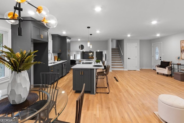 kitchen with decorative light fixtures, a wealth of natural light, light hardwood / wood-style floors, and sink