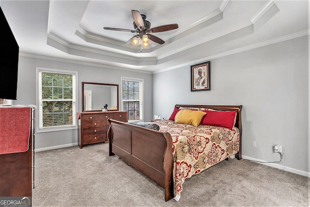 carpeted bedroom with a tray ceiling, ceiling fan, and crown molding