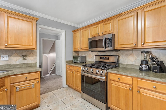 kitchen with backsplash, light tile patterned flooring, stainless steel appliances, and ornamental molding