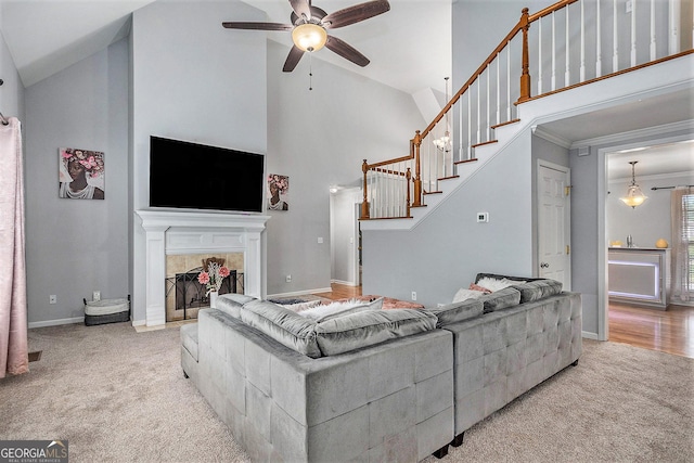 carpeted living room featuring a tiled fireplace, ceiling fan, high vaulted ceiling, and ornamental molding