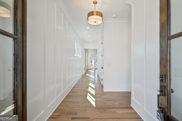 hallway with recessed lighting, a decorative wall, and light wood finished floors