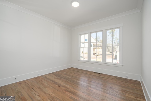 empty room featuring visible vents, crown molding, and wood finished floors