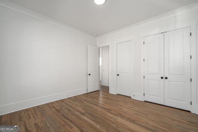 unfurnished bedroom featuring baseboards, ornamental molding, and wood finished floors