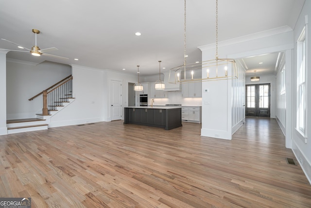 kitchen with visible vents, open floor plan, light countertops, and ornamental molding