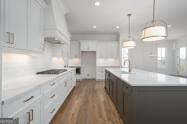 kitchen with custom exhaust hood, white cabinets, a sink, and ornamental molding