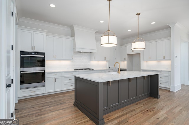 kitchen with custom exhaust hood, black cooktop, stainless steel double oven, white cabinetry, and a sink