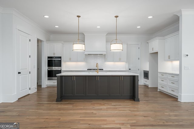 kitchen with white cabinetry, premium range hood, appliances with stainless steel finishes, and light countertops