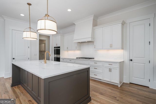 kitchen featuring appliances with stainless steel finishes, ornamental molding, wood finished floors, custom exhaust hood, and white cabinetry