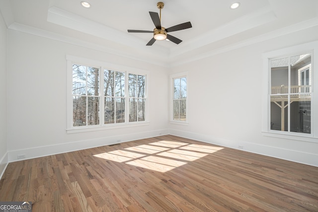 unfurnished room featuring ornamental molding, a raised ceiling, baseboards, and wood finished floors