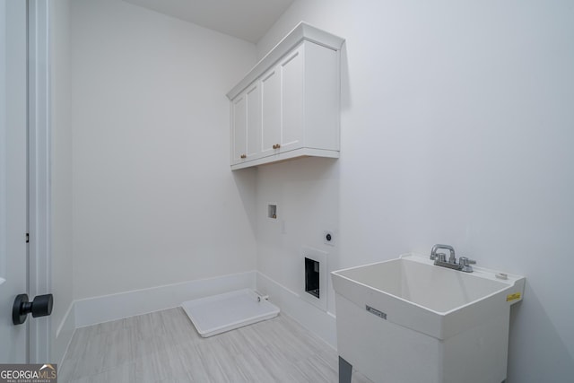 washroom with cabinet space, baseboards, hookup for an electric dryer, washer hookup, and a sink