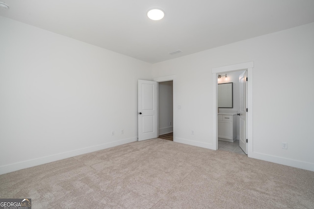 unfurnished bedroom with light carpet, ensuite bath, visible vents, and baseboards