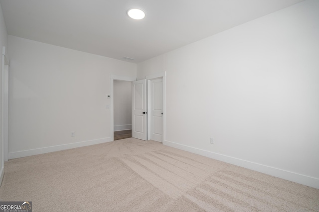 unfurnished room with baseboards and light colored carpet