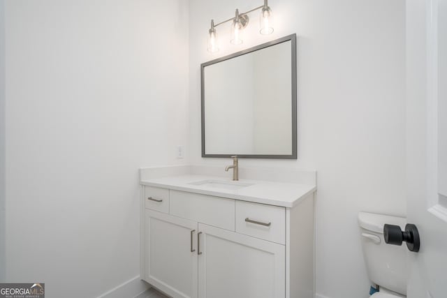 bathroom with baseboards, vanity, and toilet