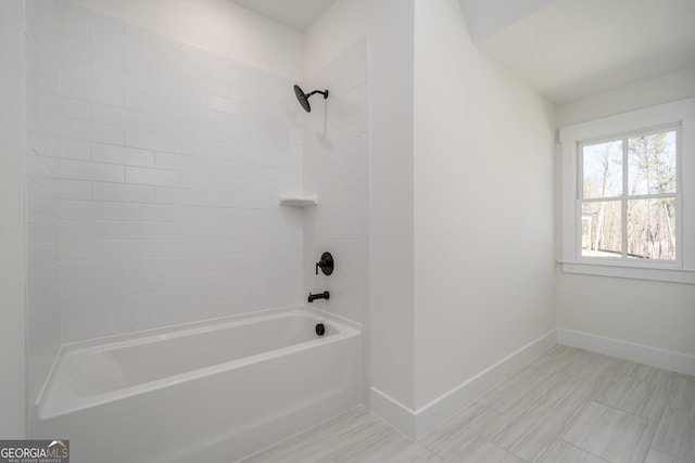 bathroom with bathing tub / shower combination and baseboards