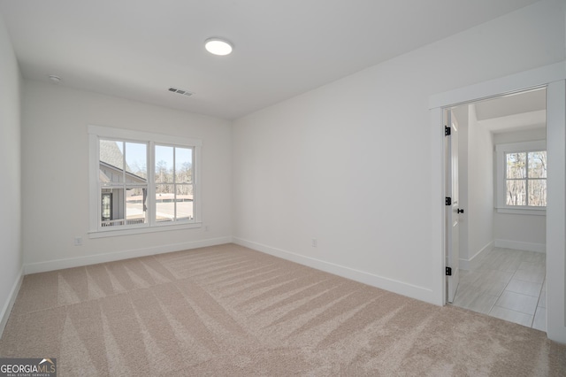 carpeted spare room featuring visible vents and baseboards