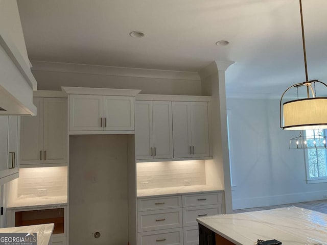 kitchen featuring backsplash, light stone counters, white cabinets, and decorative light fixtures