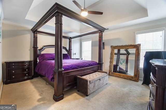 bedroom with ceiling fan, crown molding, light carpet, and a tray ceiling