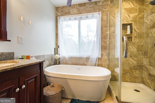 bathroom with ceiling fan, tile patterned flooring, vanity, independent shower and bath, and tile walls