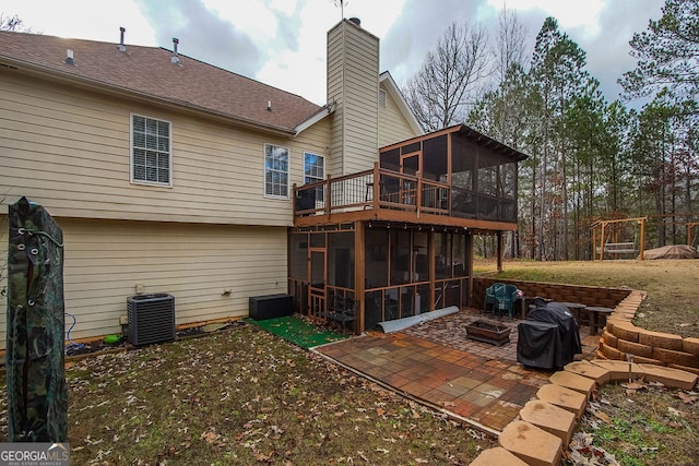 back of house featuring central air condition unit, a patio area, a sunroom, and an outdoor fire pit