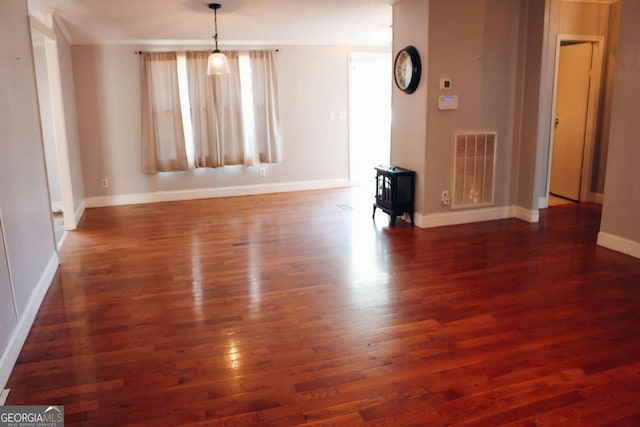 unfurnished room featuring a wood stove and dark wood-type flooring