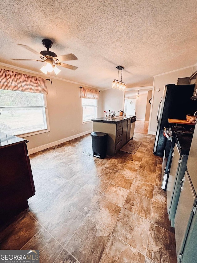 kitchen with pendant lighting, ceiling fan, ornamental molding, an island with sink, and a textured ceiling