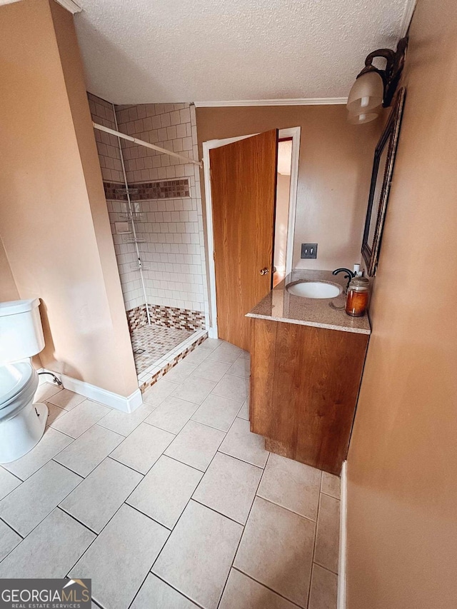 bathroom with vanity, a textured ceiling, tiled shower, and tile patterned flooring