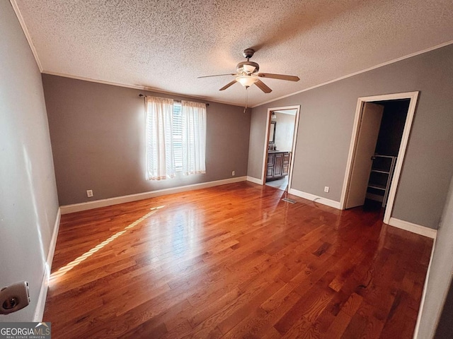 interior space with a textured ceiling, ceiling fan, dark hardwood / wood-style floors, and ornamental molding