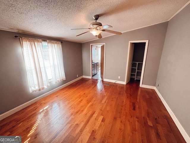 unfurnished room featuring a textured ceiling, ceiling fan, crown molding, hardwood / wood-style flooring, and lofted ceiling