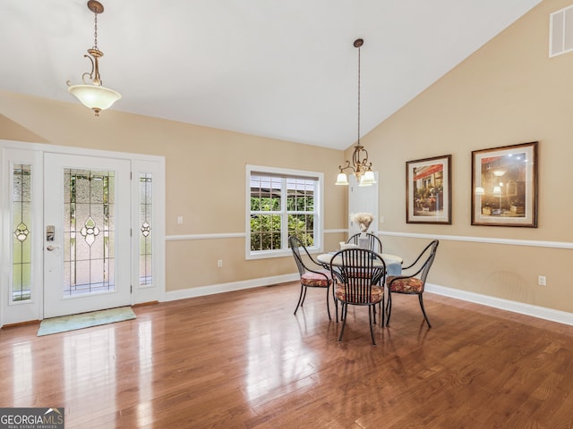 dining space featuring a chandelier, vaulted ceiling, and wood-type flooring