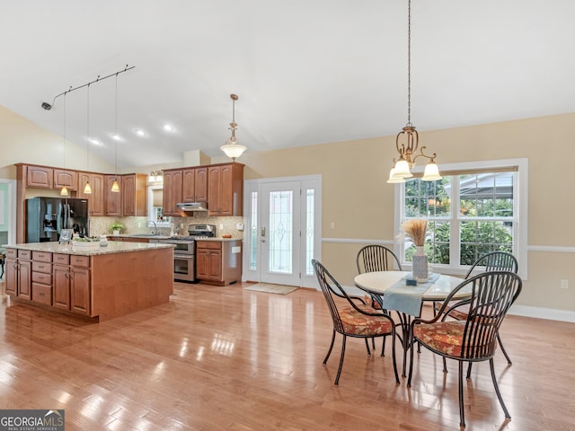 kitchen with pendant lighting, backsplash, black refrigerator with ice dispenser, stainless steel range, and a notable chandelier