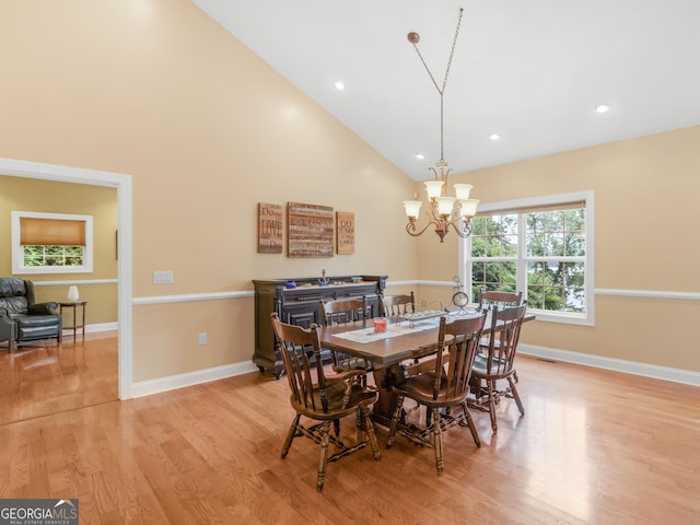 dining room featuring light wood-type flooring, high vaulted ceiling, and an inviting chandelier