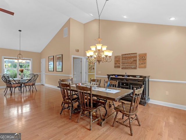 dining room with high vaulted ceiling, light hardwood / wood-style flooring, and a notable chandelier