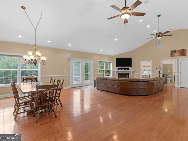 dining area with ceiling fan with notable chandelier, vaulted ceiling, and light hardwood / wood-style flooring