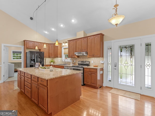 kitchen featuring pendant lighting, stainless steel stove, black fridge, and sink