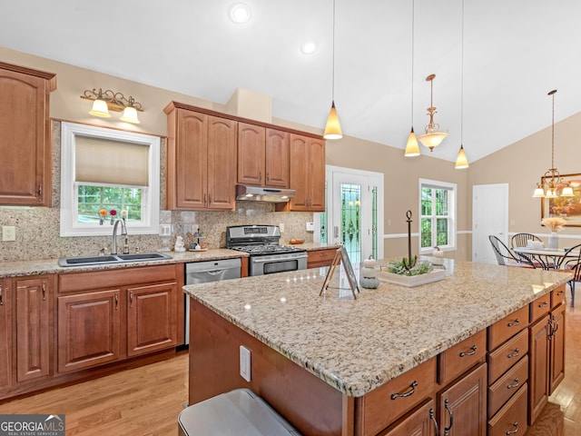 kitchen with backsplash, hanging light fixtures, sink, appliances with stainless steel finishes, and a kitchen island