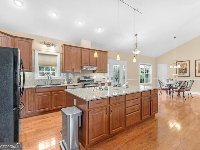 kitchen with decorative light fixtures, black fridge, sink, and stainless steel gas range