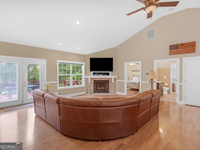 living room featuring high vaulted ceiling, french doors, light hardwood / wood-style flooring, ceiling fan, and a premium fireplace