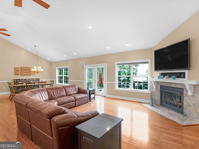 living room featuring french doors, a fireplace, vaulted ceiling, and light hardwood / wood-style flooring