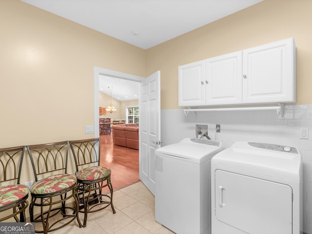 laundry room with a chandelier, light tile patterned floors, separate washer and dryer, and cabinets