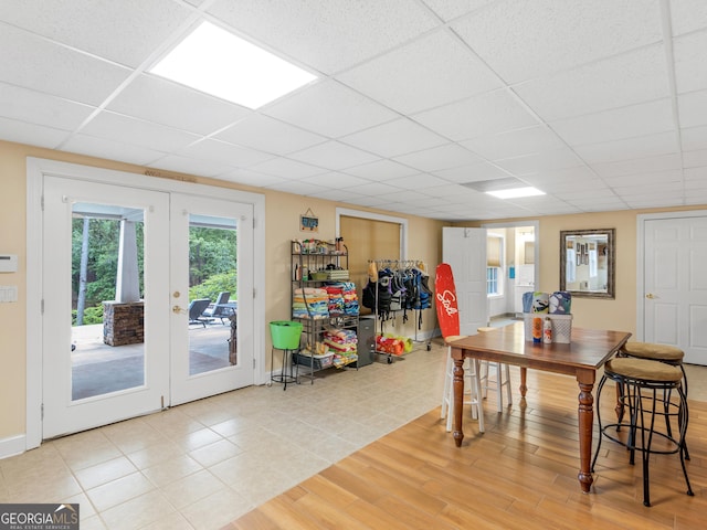 dining space with hardwood / wood-style flooring, a drop ceiling, and french doors