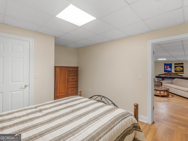 bedroom with a drop ceiling and light hardwood / wood-style flooring